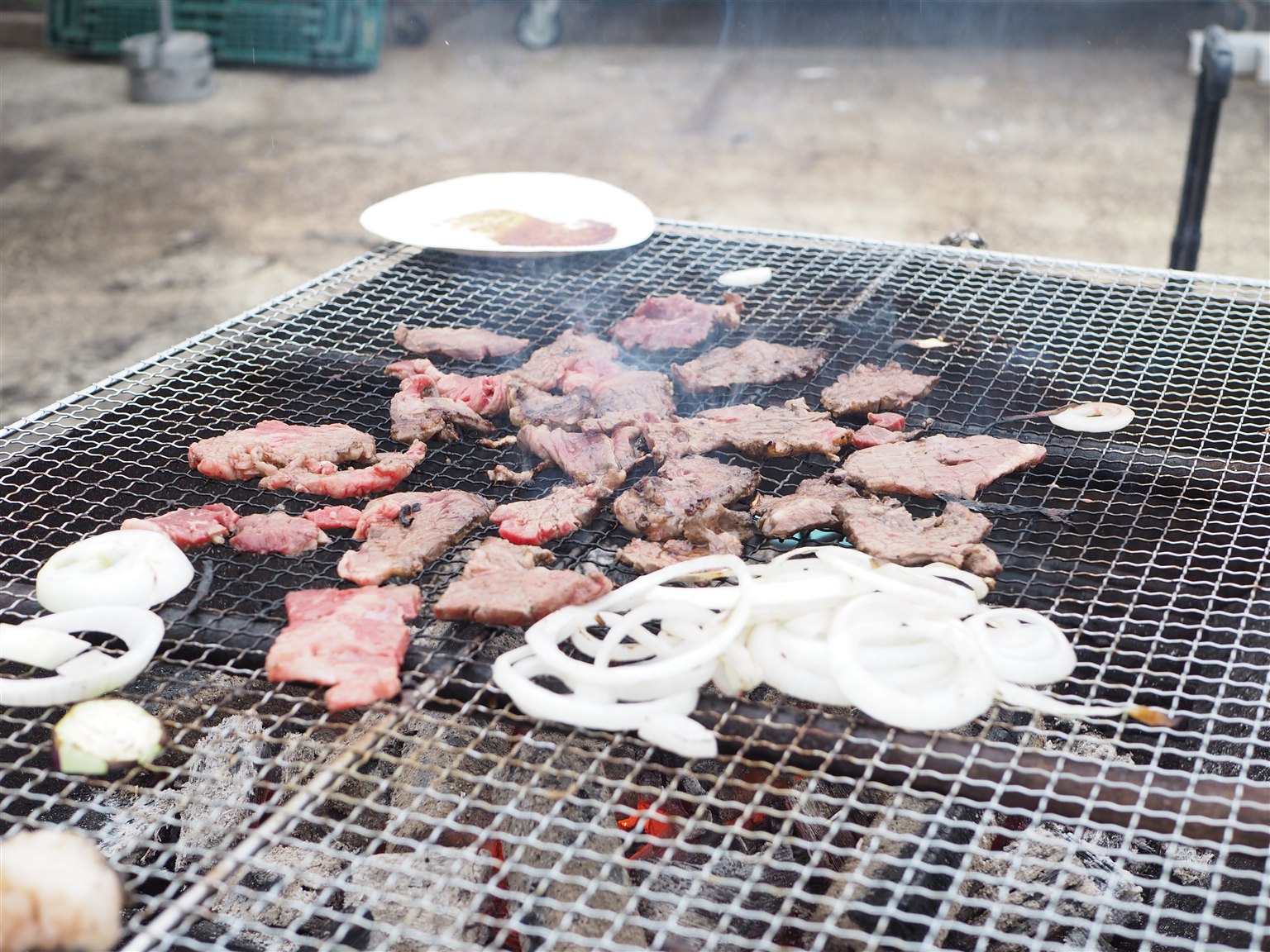炭火で肉や野菜を焼くバーベキューの様子