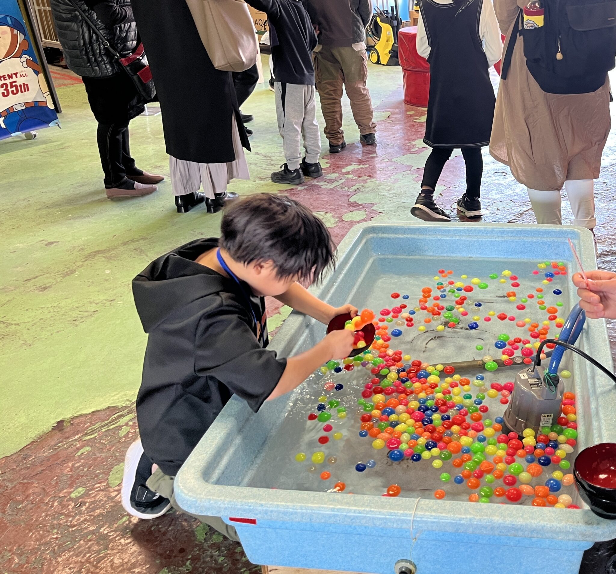 水槽でスーパーボールすくいを楽しむ子ども(MRT親子バスツアー)