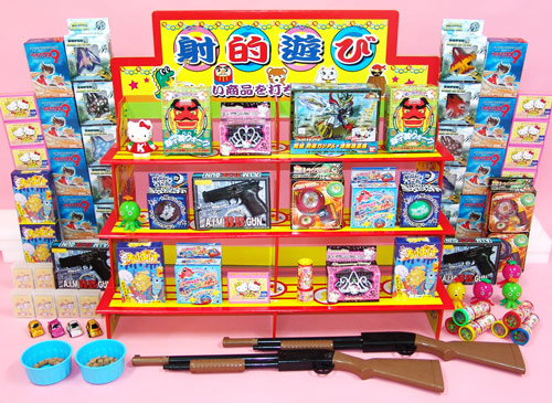 射的コーナーの景品台に景品を並べた様子とコルク銃
